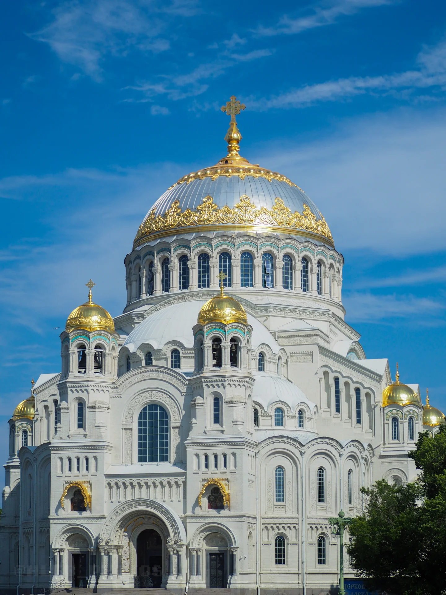Главный фасад крупного белого собора с центральным золотым куполом и арочными окнами.