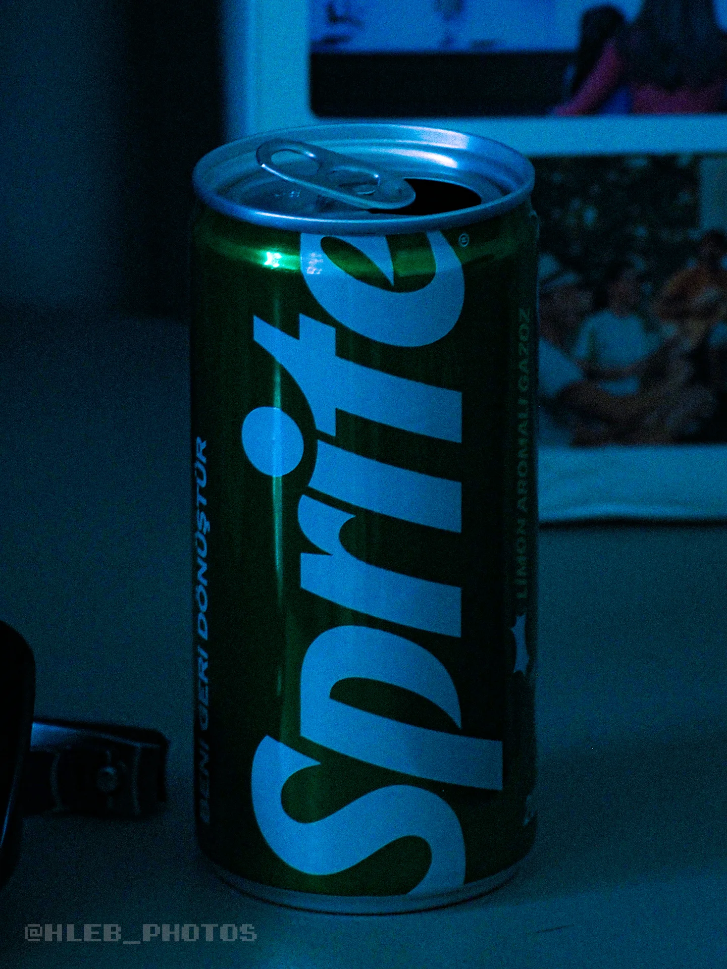 Банка Sprite крупным планом в тусклом свете.