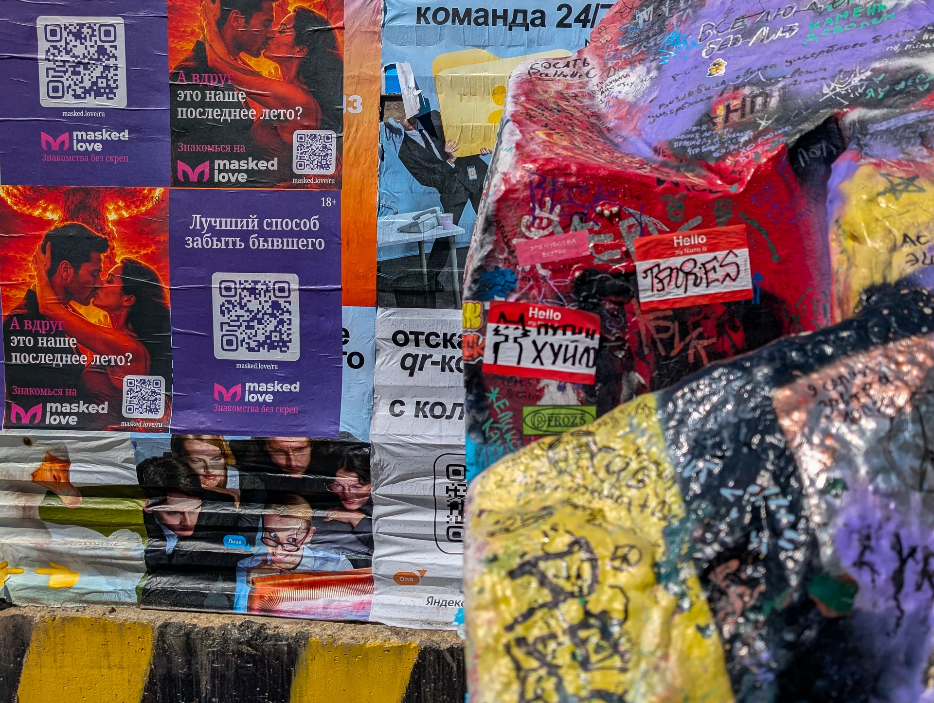 Множество разноцветных плакатов и листовок, плотно наклеенных на городскую поверхность.(Котик и "Путин *****")
