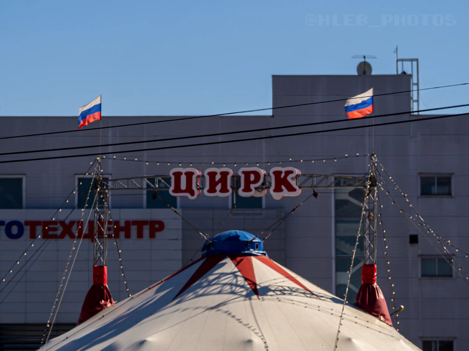Верхушка циркового шатра с установленными на мачтах флагами России.
