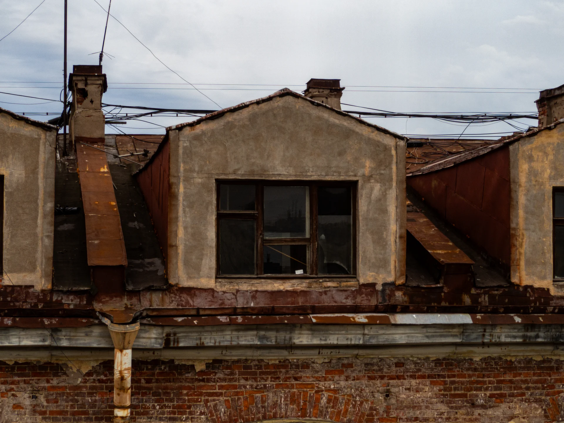 Окно мансарды на фоне черепичной крыши старинного городского дома.