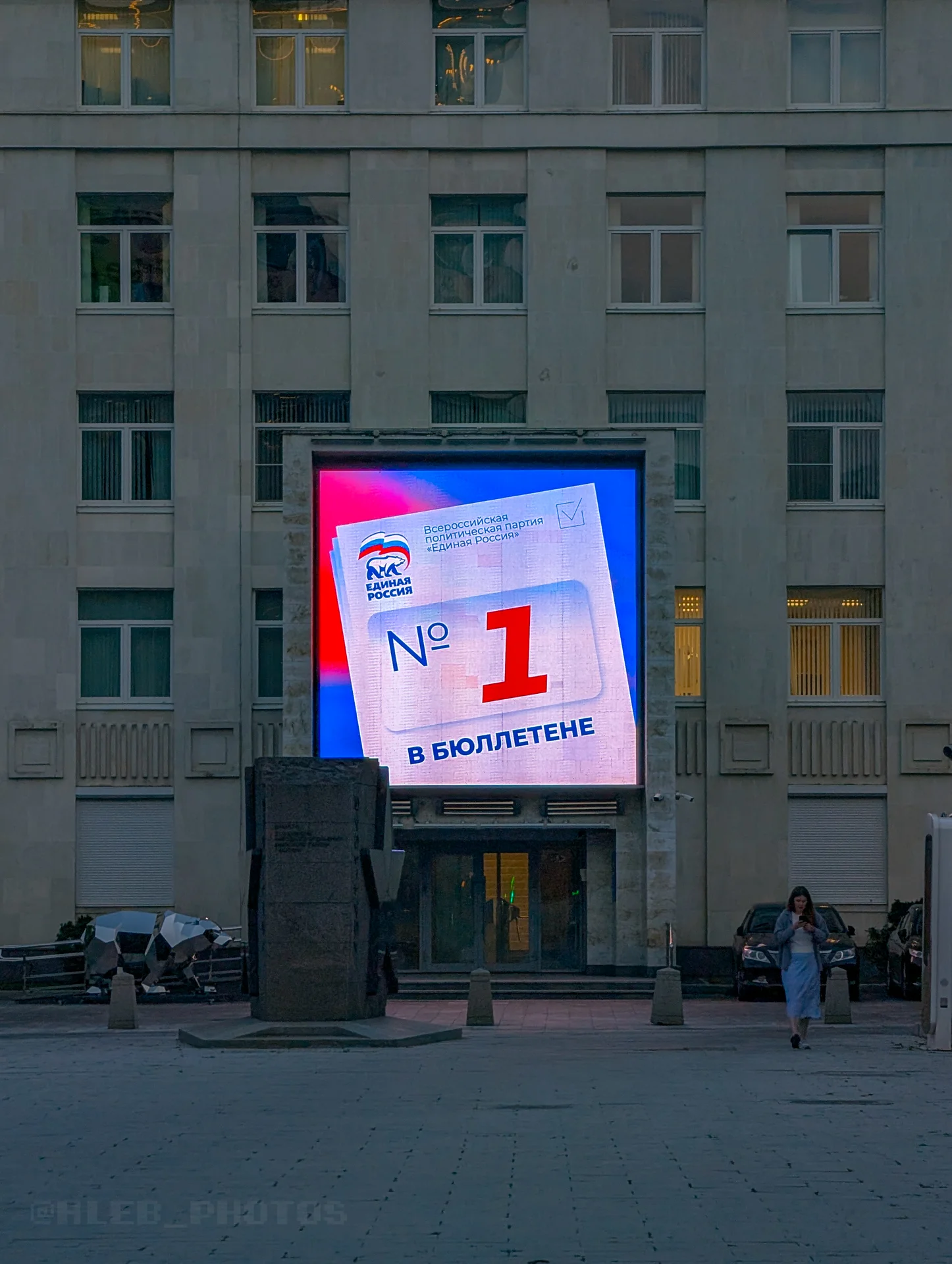 Яркий уличный рекламный экран на фасаде крупного городского здания в вечернее время.(Единая Россия. Номер 1 в бюллетене)